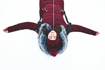 kvinde liggende på sne, våben åben, rød vinterfrakke, Vinter ro, sne scene, fredeligt øjeblik, Udendørs vinteraktivitet, sne engel positur, vinter tøj, Hyggelig vinter, Serene vinterscene