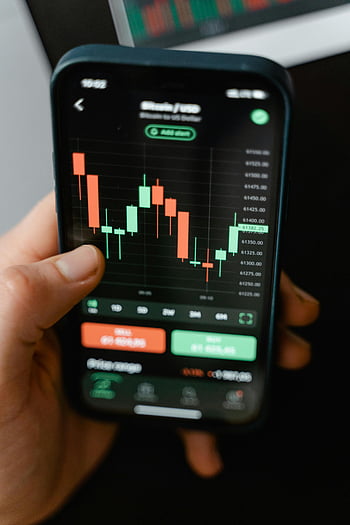 hand holding smartphone, cryptocurrency trading, trading graph, app display, Android smartphone, financial data, Bitcoin, USD, market analysis, mobile finance, stock chart