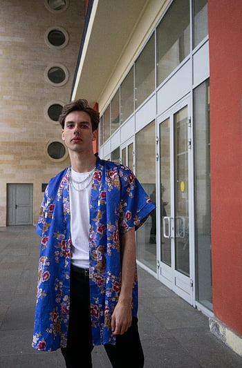 blue floral polo, fashionable man, urban backdrop, modern style, confident pose, floral shirt, stylish outfit, urban fashion, blue shirt, men's fashion, city style