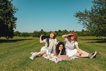 Donne sedute sull'erba, giorno soleggiato, campo, il computer portatile, giovani donne, all'aperto, picnic, natura, casuale, amici, rilassamento