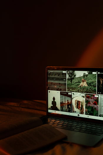 laptop screen, dark room, glowing display, various images, moody atmosphere, open book, dim lighting, indoor setting, technology use, image gallery, ambient light