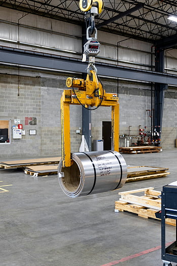 metal crane, metal coil, industrial manufacturing, crane lifting, industrial facility, manufacturing plant, metal lifting, industrial equipment, warehouse interior, metal processing, industrial machinery