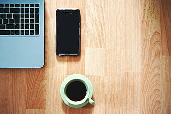 weißer Keramikbecher, schwarzes Smartphone, ordentlicher Arbeitsbereich, Laptop, Kaffeetasse, Holztisch, Arbeitsbereich einrichten, Schreibtisch, Minimalistischer Schreibtisch, Schreibtischorganisation, Kaffee und Telefon