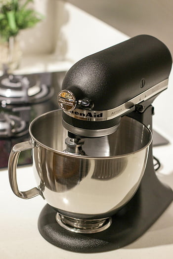 KitchenAid stand mixer, black and silver, white surface, modern kitchen, baking needs, stylish mixer, Artisan model, stainless steel bowl, countertop appliance, home baking, kitchen tools