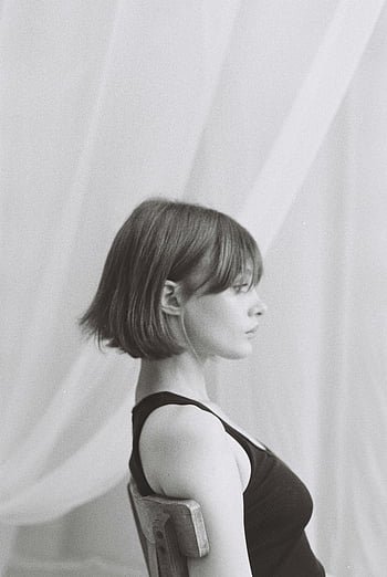 Kvinna med kort hår, sitter på stol, svartvitt porträtt, elegant, inomhus-, mjuk belysning, svartvit, sittande kvinna, porträttfotografi, minimalistisk, lugn
