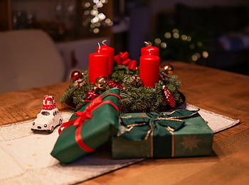 Vánoce, červené svíčky, Zelené dárkové boxy, dřevěný stůl, Útulná scéna, sváteční dekorace, adventní svíčky, Slavnostní prostředí, vánoční dárky, vánoční věnec, vánoční ozdoby