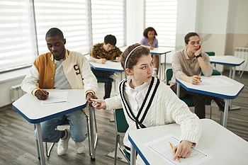 tahák, Zkouška ve třídě, pokus o podvádění, rozmanité studenti, dívka podvádí, vyhlíží, interakce se spolužáky, Akademická nečestnost, testování, chování studentů, zkušební místnost
