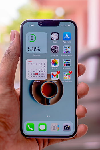 Apple iPhone, smartphone, hand holding, app icons, battery percentage, calendar widget, mobile device, iOS interface, digital apps, phone screen, user interface