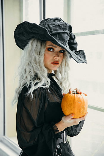 woman in black witch hat, Halloween pumpkin, witch costume, indoor Halloween, Halloween spirit, black dress, Halloween photo, Halloween costume, woman holding pumpkin, Halloween indoor, witch holding pumpkin