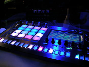 DJ mixer, illuminated DJ mixer, LED pads, vibrant LED pads, dark studio environment, close-up DJ mixer, Pioneer DJ, music production, electronic music, DJ equipment, studio lighting