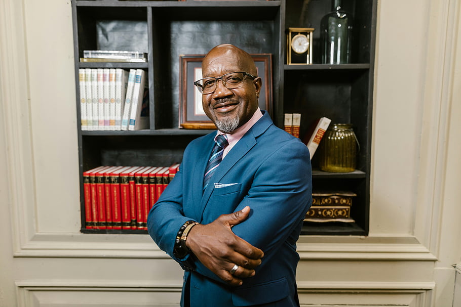 man portrait, mature businessman, glasses, confident smile, elegant office, bookshelf background, professional attire, business suit, office setting, corporate image, leadership qualities