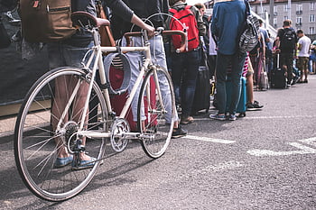 black sweater, grey road bike, diverse group, adults, city street, urban life, lined up, city scene, bicycle, street scene, people