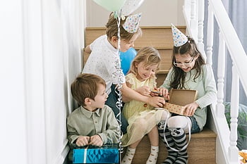 children opening gifts, staircase, birthday party, indoor celebration, kids, balloons, party hats, festive atmosphere, gift boxes, happy children, family gathering
