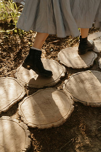 donna negli stivali, stivali neri, fette di tronchi di legno, foresta soleggiata, camminare sui tronchi, vestito, ambientazione esterna, natura, sentiero nel bosco, ceppi d'albero, luce del sole