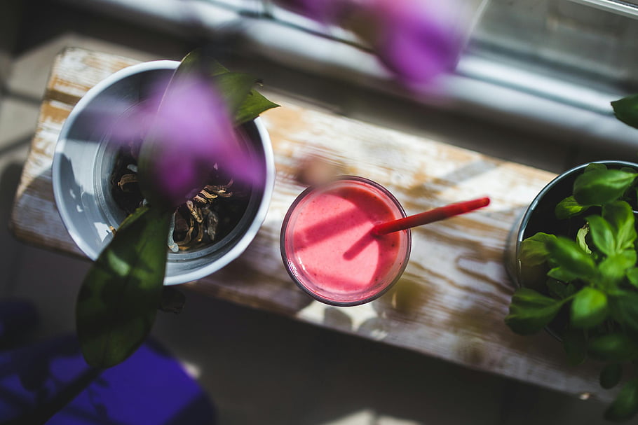 strawberry yogurt, vibrant smoothie, top view, greenery, healthy lifestyle, smoothie bowl, fresh drink, plant background, natural light, healthy eating, strawberry smoothie