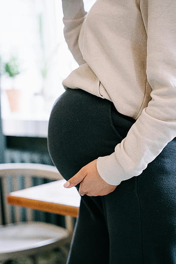 gravid kvinne, svarte bukser, hvit genser, holder magen, side profil, forsiktig berøring, barselmote, graviditetsstil, ventende mor, Belly Bump, Uformelt antrekk