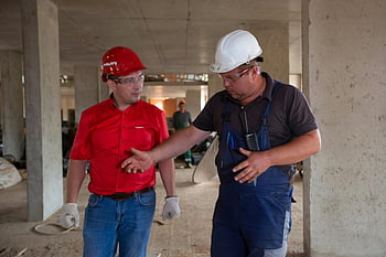 construction site, safety gear, construction workers, discussing plans, hard hats, work environment, industrial setting, building site, construction equipment, teamwork, safety equipment