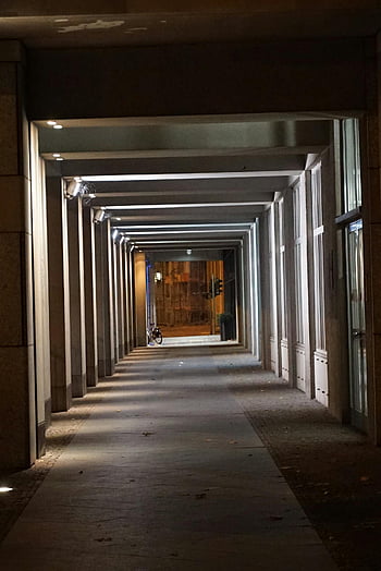 concrete building hallway, empty corridor, linear architecture, geometric patterns, night lighting, moody ambiance, urban corridor, modern architecture, concrete structure, night scene, architectural photography