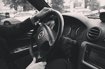 grayscale photography, person driving, car interior, luxury car, steering wheel, driver's hands, black and white, detailed photo, vehicle interior, automotive photography, car dashboard