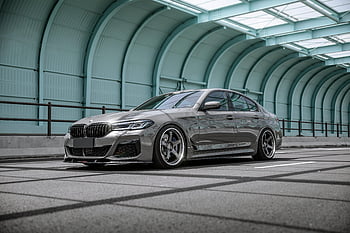 Gray BMW, luxury sedan, modern road, skybridge, sleek design, engineering, urban setting, car photography, automotive design, street scene, vehicle showcase