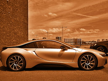 Brown Coupe, luxury sports car, sleek design, parked outdoors, sepia tone, artistic touch, modern vehicle, urban setting, high-end car, stylish automobile, cityscape background