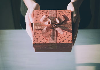 braune Geschenkbox, Blumenmuster, wunderschön verpackt, Hände präsentieren, Festgeschenk, Geschenkverpackung, festliches Geschenk, elegantes Geschenk, Geschenkbox, Blumendesign, Geschenkpräsentation