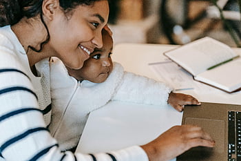 Mutter arbeitet von zu Hause aus, Multitasking -Mutter, Work-Life-Balance, lächelnde Mutter, Baby halten, Laptop-Arbeit, Innenministerium, Kind auf Schoß, Heimarbeit, Familienzeit, Produktivitätstipps