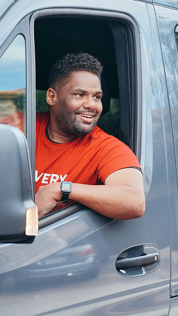 man in red shirt, sitting in van, happy delivery driver, smiling out window, positive delivery service, van window, red crew neck t-shirt, delivery driver, van interior, smiling man, delivery vibe