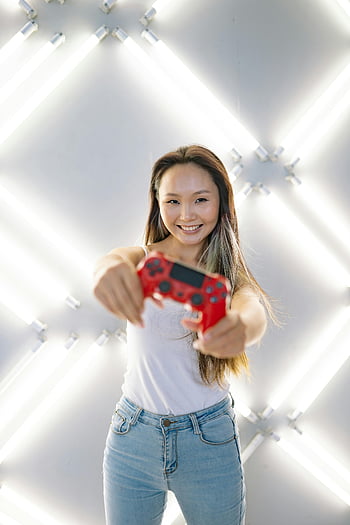 Frau, Red Game Controller, selektiver Fokus, Neon-beleuchtete Einstellung, lächelnde Frau, Gaming-Controller, moderne Einstellung, Technische Themen, Gaming -Themen, weißer Hintergrund, Lässige Kleidung