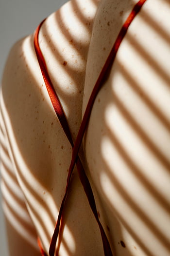 woman with freckles, back strap, sunlit shadows, artistic close-up, woman's back, cross back strap, freckled skin, natural light, shadow play, skin texture, back detail