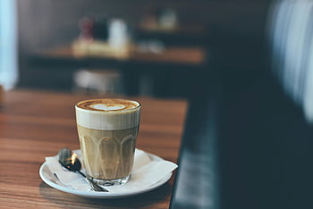 latté, art en mousse en forme de cœur, table en bois, café confortable, verre clair, boisson brune, soucoupe blanche, photographie d'inclinaison, boisson au café, CAFE RÉGLAGE, cuillère
