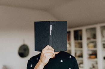 man reading, book cover face, indoor leisure, study symbol, black book, casual reading, home library, bookshelf background, relaxed reading, personal study, indoor reading