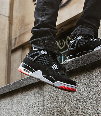 schwarze und rote Turnschuhe, Nahaufnahme, städtische Steinmauer, Streetwear Mode, stilvolle Turnschuhe, schwarze Turnschuhe, rote Akzente, urbane Mode, Sneaker -Liebhaber, Streetstyle, Sneaker-Kultur