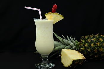 Pina Colada, Nahaufnahme, Ananasgarnitur, tropische Stimmung, Glas Piña Colada, Stroh, Ananasscheibe, tropisches Getränk, cremiger Cocktail, Fruchtgarnitur, schwarzer Hintergrund