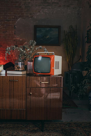 orange vintage television, brown wooden cabinet, retro vibe, classic television, nostalgic decor, mid-century furniture, vintage electronics, retro interior, orange TV, wooden furniture, vintage style