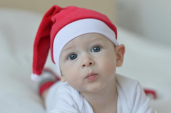 baby, red Christmas hat, white textile, blue eyes, Santa hat, festive Christmas spirit, indoor photo, cute baby, holiday photo, Christmas baby, baby photography