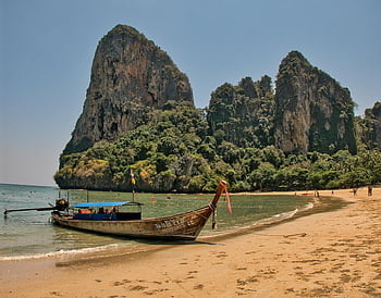 playa de railay, bote de cola larga, playa de arena, acantilados de piedra caliza, vista impresionante, playa tropical, Tailandia, paisaje costero, vacaciones en la playa, belleza natural, barco atracado