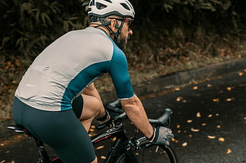 man in sportswear, helmet, riding bicycle, adult cyclist, wearing helmet, gloves, mountain bike, outdoors, paved road, cycling, sportswear