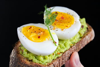 avocado toast, soft-boiled eggs, nutritious breakfast, healthy meal, sliced egg, green salad, bread, avocado spread, egg yolk, dill garnish, black background