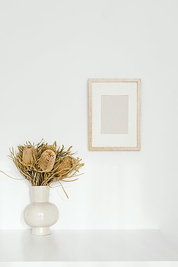Holzbilderrahmen, weiße Wand, minimalistisches Interieur, Keramikvase, getrocknete Blumen, leerer bilderrahmen, Stylish Decor, modernes Design, Wohnkultur, weiße Vase, minimalistischer Stil