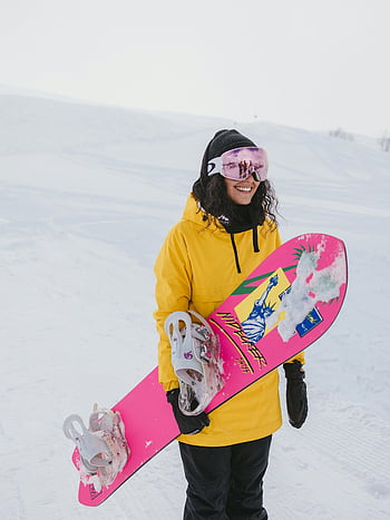 Γυναίκα σε κίτρινο hoodie, ροζ και λευκό snowboard, χαρούμενος snowboarder, χειμερινά σπόρ, χιονισμένο βουνό, χιονοσανίδα, χειμερινές δραστηριότητες, υπαίθρια αναψυχή, εξοπλισμό χιόνι, χειμερινή μόδα, ροζ snowboard