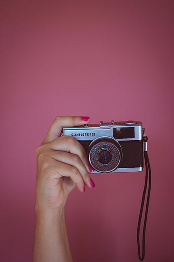 retro kamera, olympus tur 35, kvindens hånd, vintage kamera, fotografering, pink negle, sort kamera, Lyserød baggrund, Håndholdningskamera, retrofotografering