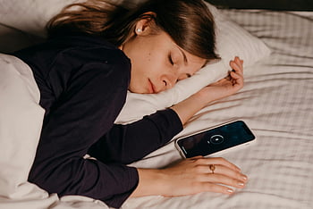 Frau schläft, Smartphone in der Nähe, friedlicher Schlaf, Bettruhe, Entspannung, Nachtschlaf, hübsche Frau, Handy neben, erholsamer Schlaf, Schlafzimmerszene, Smartphone im Bett