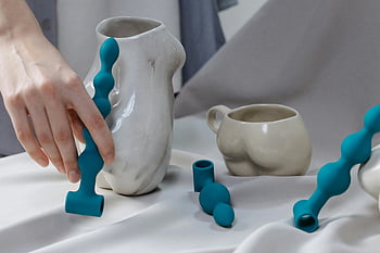 手の動き、 セラミックス、 ユニークなオブジェクト、 白い布、 青いオブジェクト、 芸術的なアレンジメント、 現代美術、 抽象的なデザイン、 触覚相互作用、 クリエイティブディスプレイ