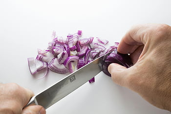 chopping onion, purple onions, white cutting board, sharp knife, close-up hands, slicing onions, food preparation, kitchen tools, culinary skills, healthy cooking, vegetable chopping