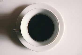 liquide noir, tasse en céramique blanche, tir minimaliste, tasse à café noire, table blanche, ambiance sereine, design épuré, vue de dessus, tasse de café, fond blanc, théâtre d'ombres
