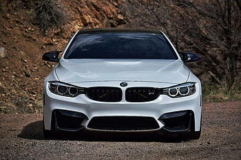 White BMW F80 M3, modern luxury car, clean front view, rocky outdoor background, white BMW, BMW M3, luxury vehicle, outdoor setting, car photography, automotive design