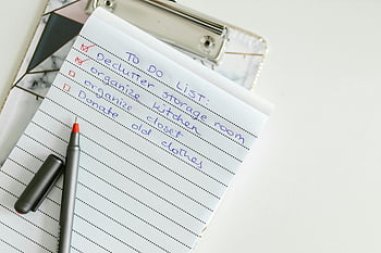 to-do list, lined paper, pen, task organization, clipboard, handwritten notes, declutter storage room, organize kitchen, donate old clothes, task management, productivity tools