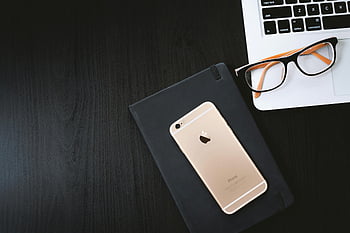Gold iPhone 6, black case, eyeglasses, silver MacBook, minimalist workspace, smartphone, laptop, wooden desk, tech setup, office accessories, productivity tools