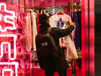 man shopping, trendy clothing, brightly lit boutique, black coat, black hat, boutique shopping, man in hat, clothing store, fashion boutique, man shopping for clothes, neon sign